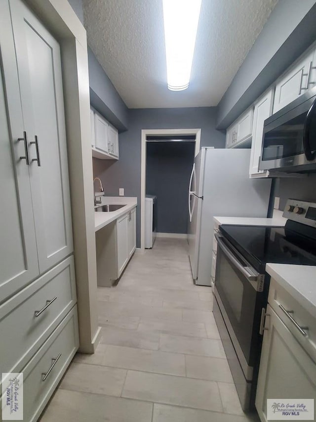 kitchen with sink, separate washer and dryer, a textured ceiling, white cabinets, and appliances with stainless steel finishes