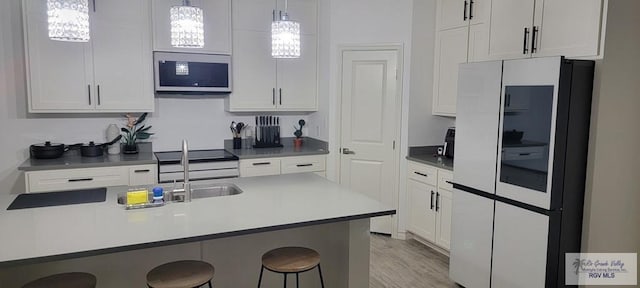 17134 Mandarin Ave, Harlingen, TX 78552 - kitchen featuring stainless steel microwave, a kitchen breakfast bar, white cabinets, and hanging light fixtures