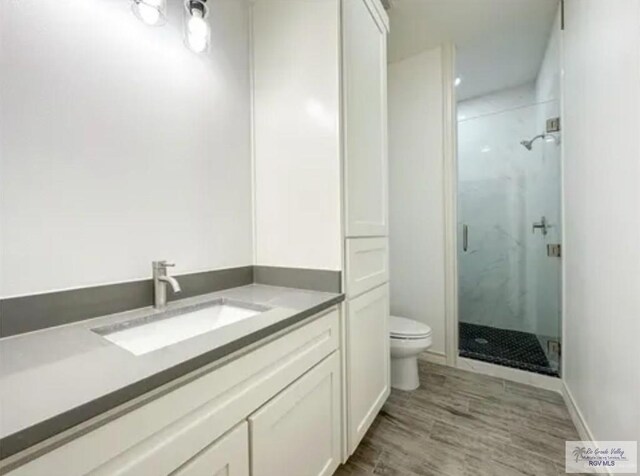 17134 Mandarin Ave, Harlingen, TX 78552 - bathroom featuring a marble finish shower, toilet, vanity, wood finished floors, and baseboards