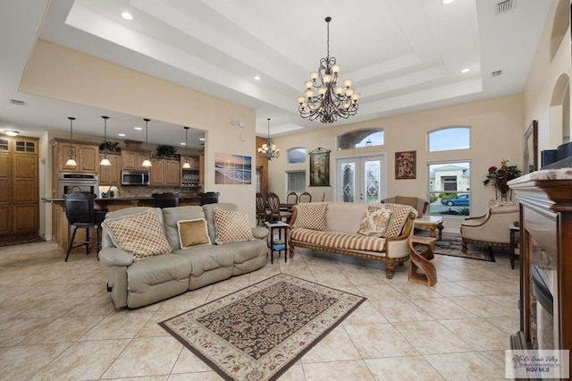 tiled living room with a raised ceiling, french doors, a towering ceiling, and a chandelier