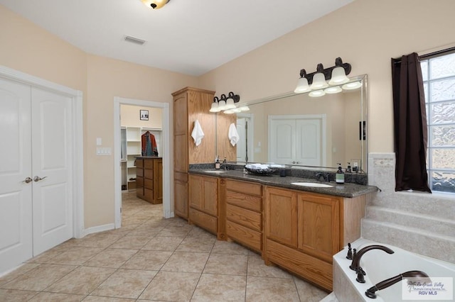 bathroom with a tub to relax in, tile patterned floors, and vanity