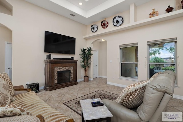 living room featuring a high end fireplace, a towering ceiling, and light tile patterned flooring