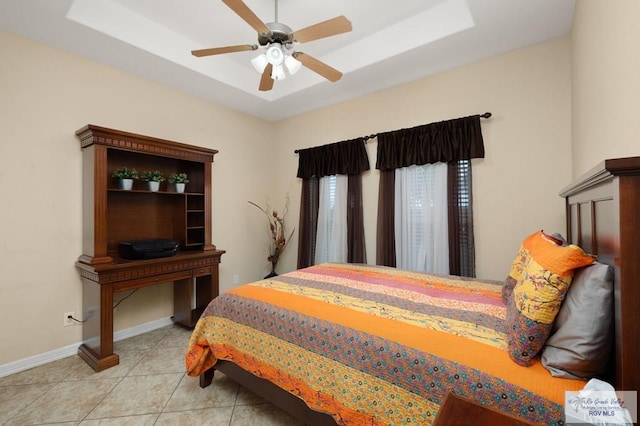 bedroom with ceiling fan, light tile patterned flooring, and a tray ceiling