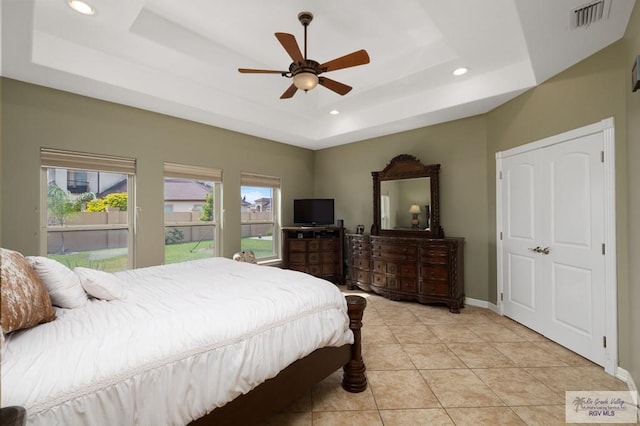 tiled bedroom with a raised ceiling and ceiling fan