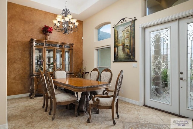 dining room with french doors, light tile patterned floors, an inviting chandelier, and a high ceiling