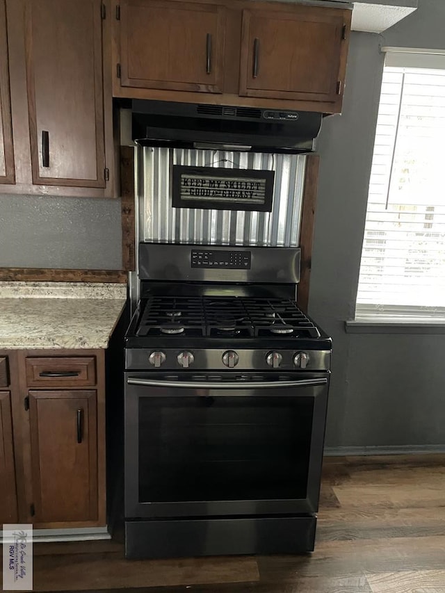 kitchen with hardwood / wood-style floors, exhaust hood, and stainless steel range with gas stovetop