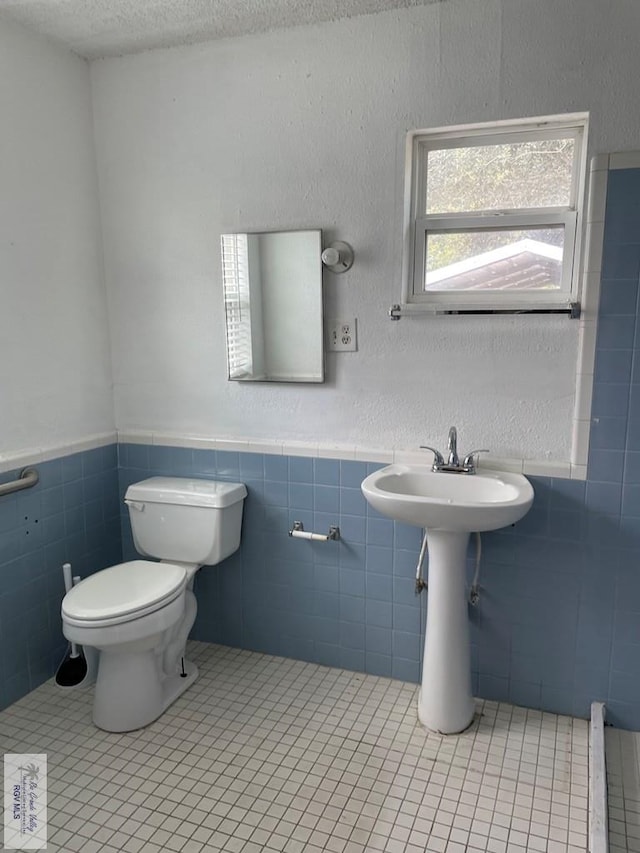 bathroom featuring tile walls, tile patterned floors, a textured ceiling, and toilet