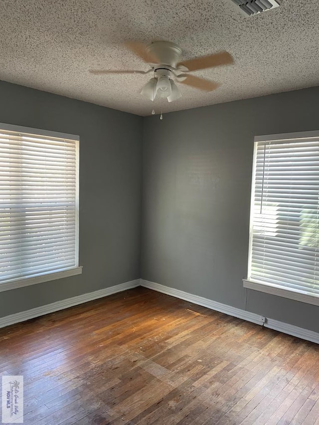 unfurnished room with ceiling fan, dark hardwood / wood-style flooring, and a textured ceiling