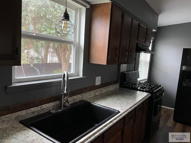 kitchen featuring dark brown cabinetry, sink, dark wood-type flooring, and black appliances