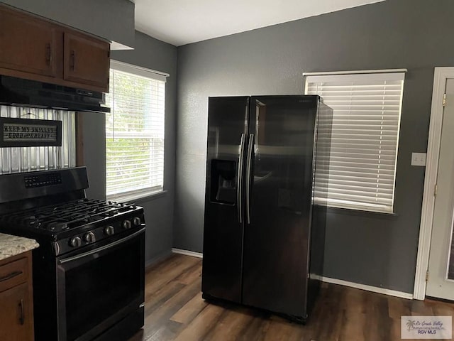 kitchen featuring gas stove, dark hardwood / wood-style floors, extractor fan, and fridge with ice dispenser