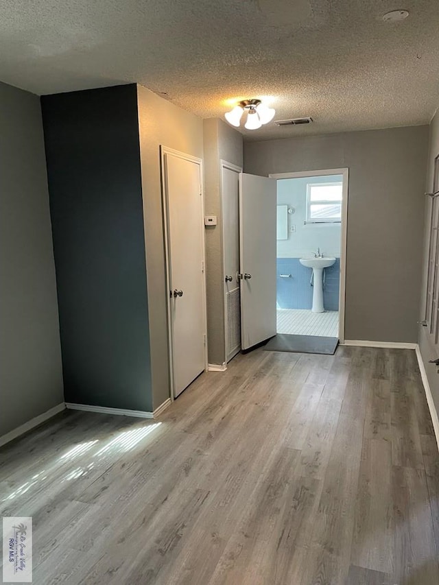 interior space featuring hardwood / wood-style flooring, ensuite bath, and a textured ceiling