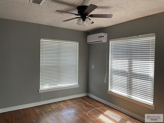 unfurnished room with wood-type flooring, a wall mounted AC, a textured ceiling, and ceiling fan