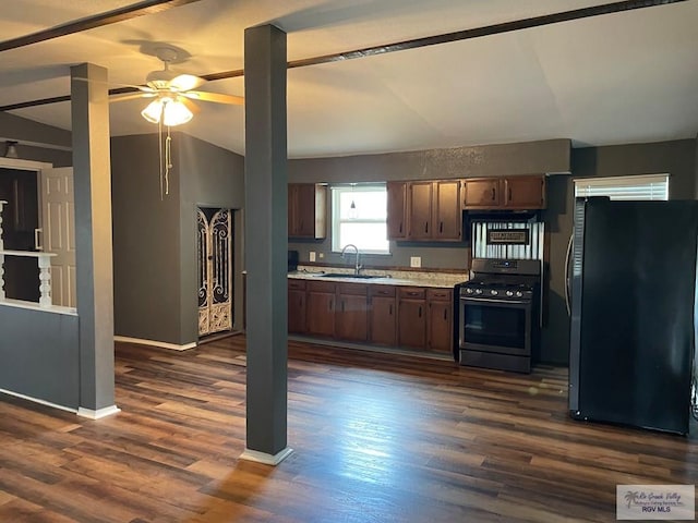 kitchen featuring sink, dark wood-type flooring, stainless steel gas range, fridge, and vaulted ceiling