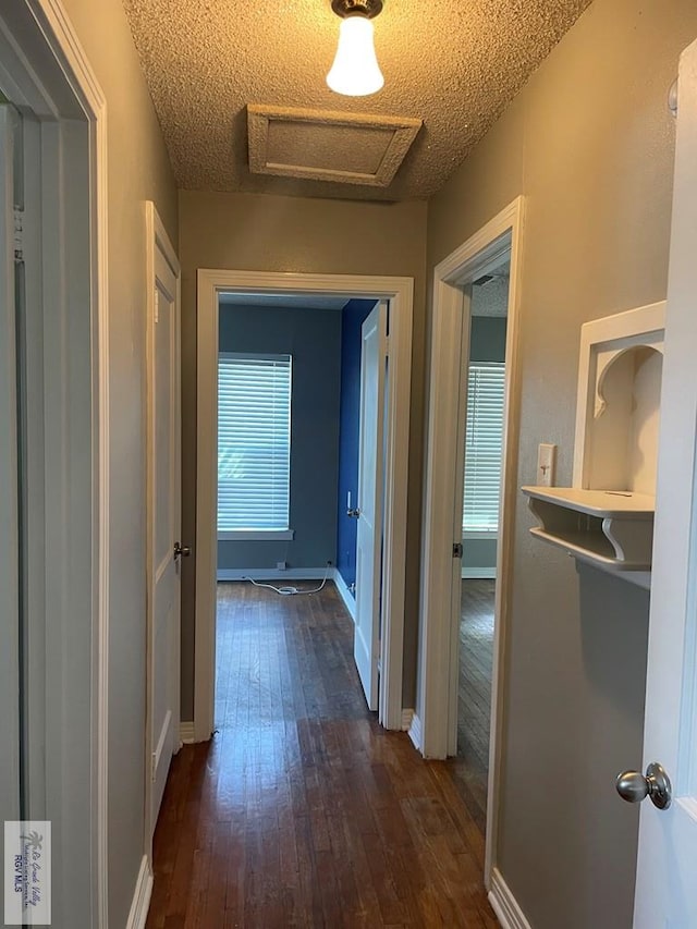 hallway with dark hardwood / wood-style floors and a textured ceiling