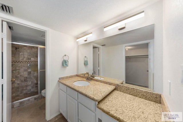 bathroom with vanity, toilet, and a shower with door