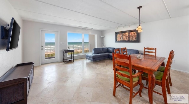 dining room featuring rail lighting and a water view