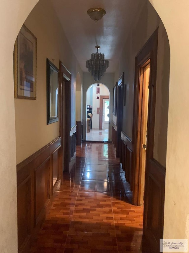 2310 Tiffany Dr, Mission, TX 78574 - hallway with arched walkways, a chandelier, wainscoting, a decorative wall, and wood finished floors
