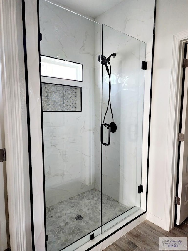 bathroom with wood-type flooring and an enclosed shower