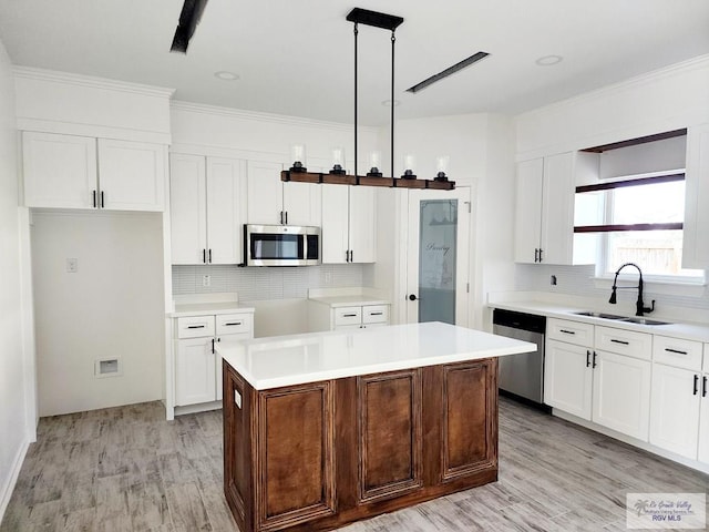 kitchen with sink, white cabinetry, decorative light fixtures, a center island, and stainless steel appliances