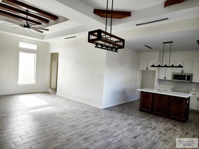 kitchen featuring white cabinetry, a center island, hanging light fixtures, light hardwood / wood-style flooring, and ceiling fan