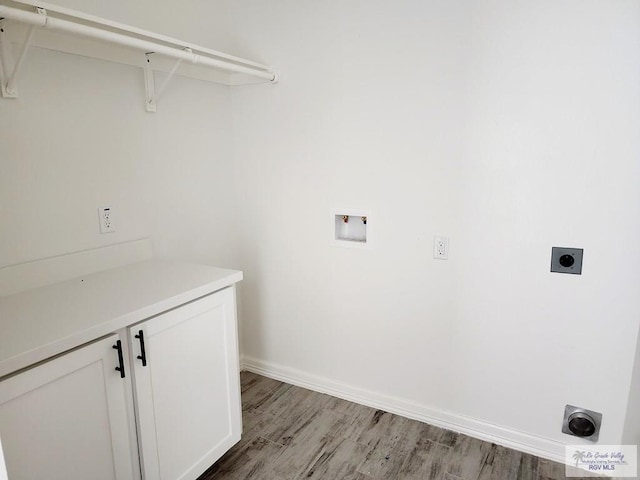 clothes washing area with electric dryer hookup, hookup for a washing machine, light hardwood / wood-style flooring, and cabinets