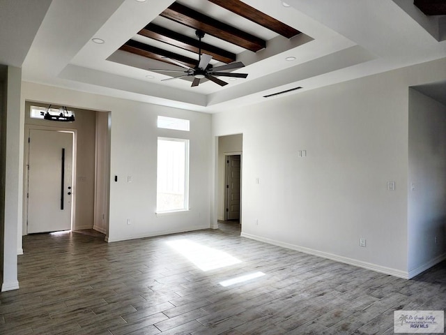 unfurnished room featuring hardwood / wood-style flooring, beam ceiling, a towering ceiling, ceiling fan with notable chandelier, and a raised ceiling