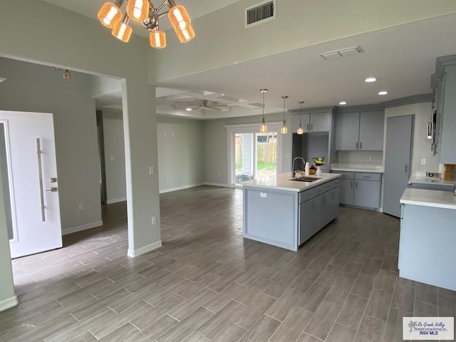 kitchen with gray cabinets, light countertops, visible vents, open floor plan, and a sink