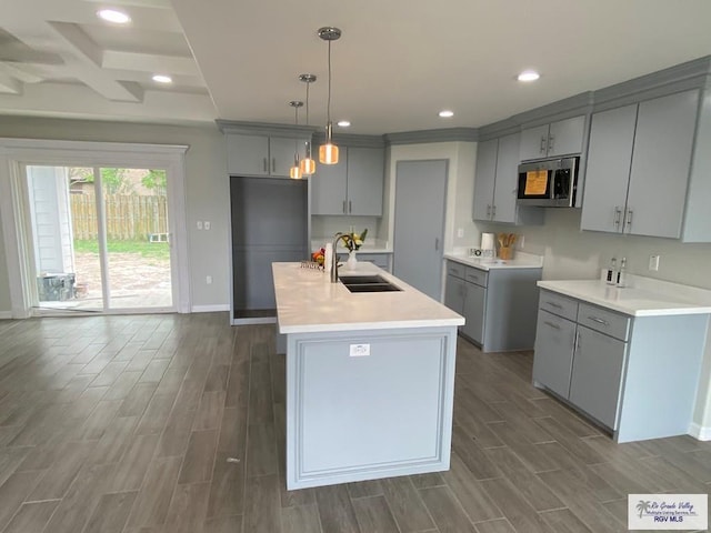 kitchen featuring wood tiled floor, gray cabinets, stainless steel microwave, and a sink