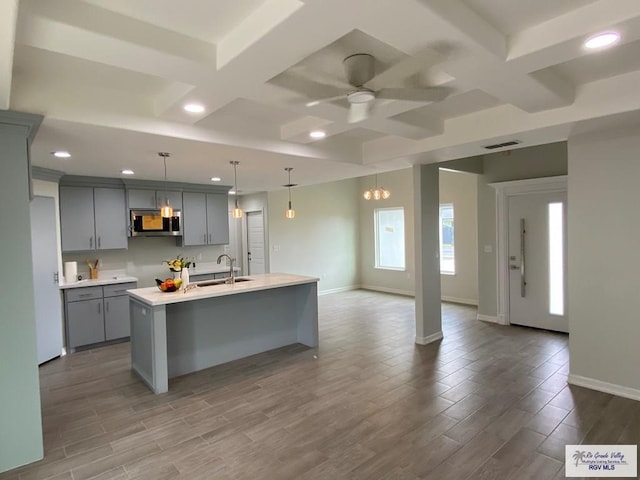 kitchen featuring a sink, stainless steel microwave, gray cabinets, and visible vents