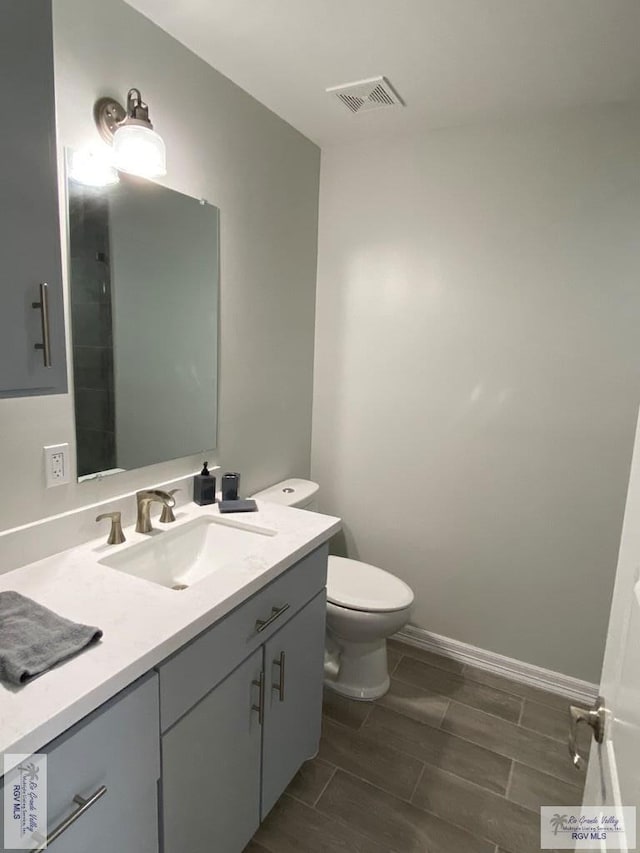 bathroom featuring baseboards, visible vents, vanity, and toilet