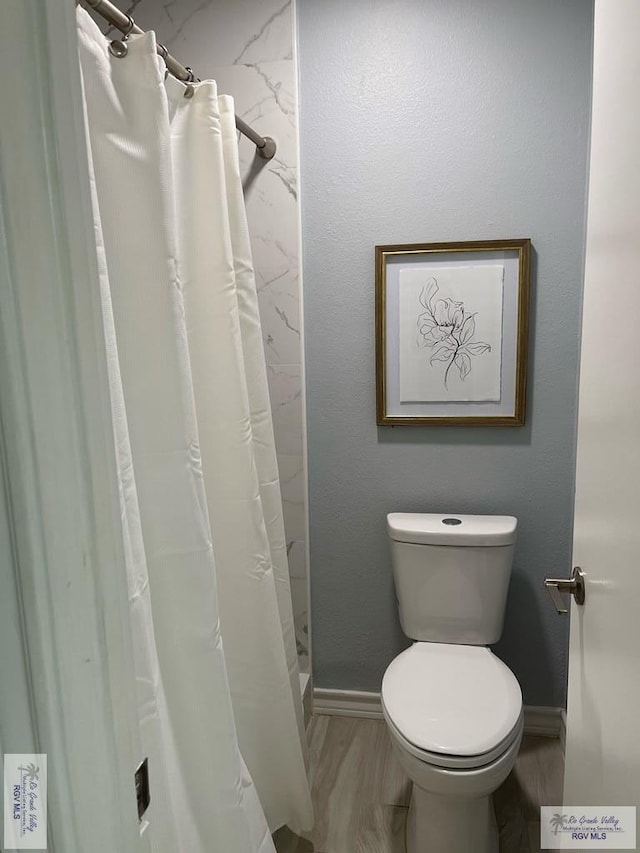 bathroom featuring hardwood / wood-style floors, toilet, and a shower with shower curtain