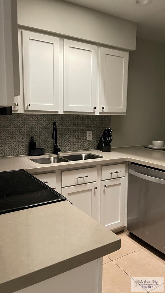 kitchen featuring sink, light tile patterned floors, tasteful backsplash, white cabinets, and stainless steel dishwasher