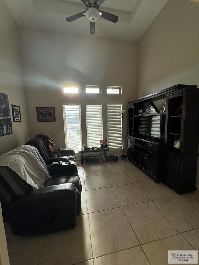 tiled living room featuring ceiling fan and high vaulted ceiling