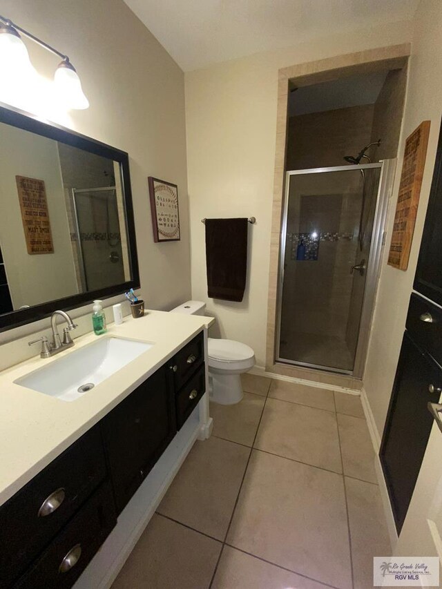 bathroom featuring toilet, vanity, tile patterned floors, and walk in shower