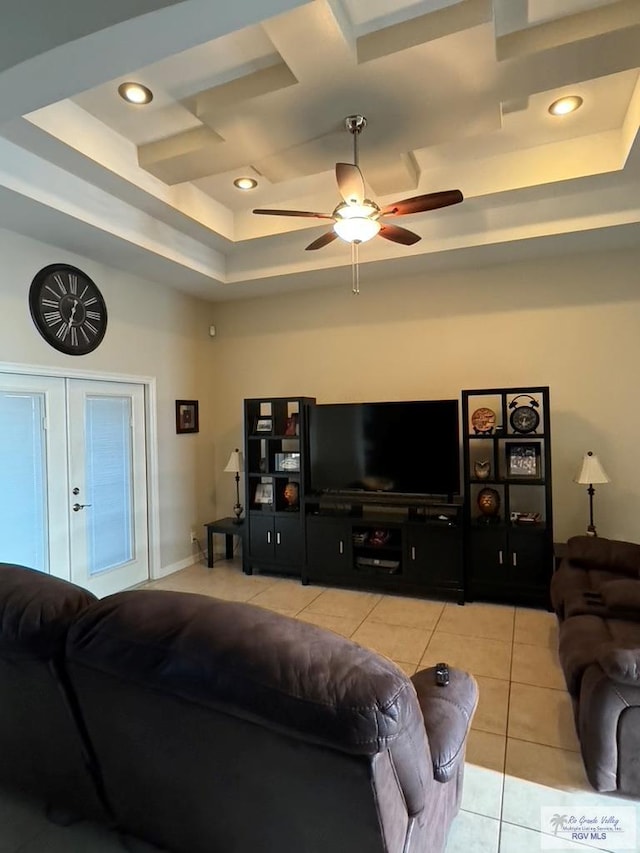 living room with ceiling fan, a raised ceiling, and light tile patterned floors