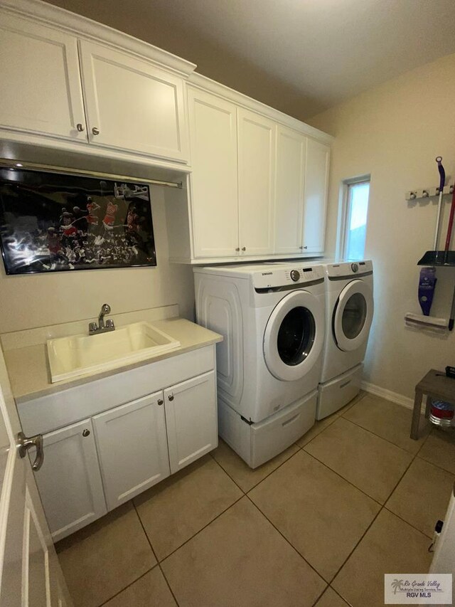 clothes washing area featuring washer and clothes dryer, light tile patterned flooring, cabinets, and sink