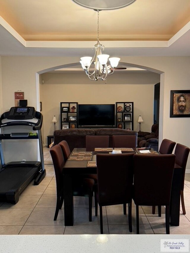 dining area featuring light tile patterned floors, a raised ceiling, and a notable chandelier