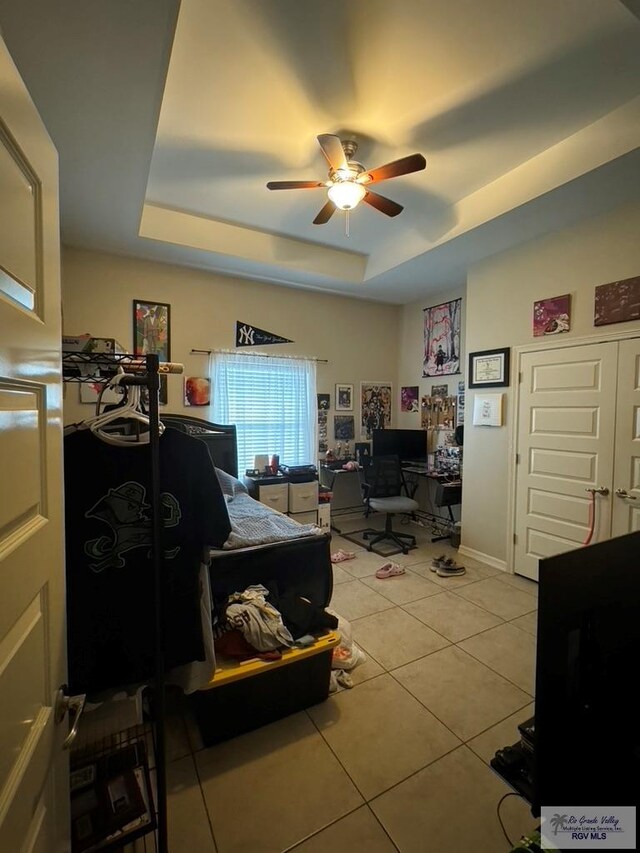 tiled home office with a tray ceiling and ceiling fan