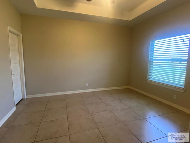 116 Village E Dr, Los Fresnos, TX 78566 - empty room featuring a tray ceiling, ceiling fan, light tile patterned floors, and baseboards
