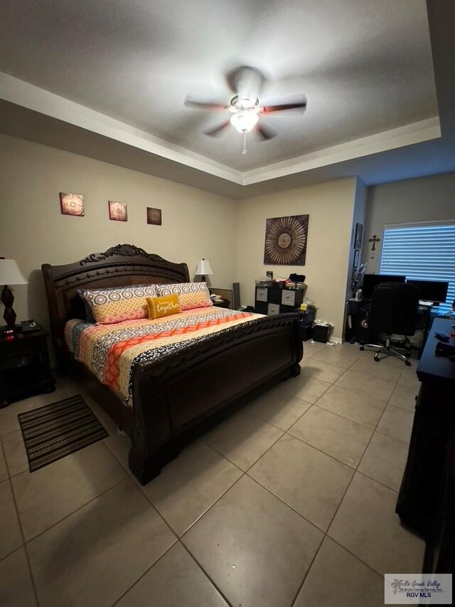 tiled bedroom featuring a tray ceiling and ceiling fan