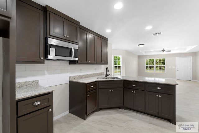 kitchen with sink, ceiling fan, backsplash, dark brown cabinetry, and kitchen peninsula