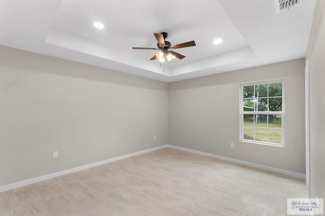 empty room featuring a tray ceiling and ceiling fan