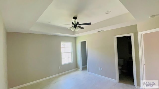 unfurnished bedroom with ceiling fan and a raised ceiling