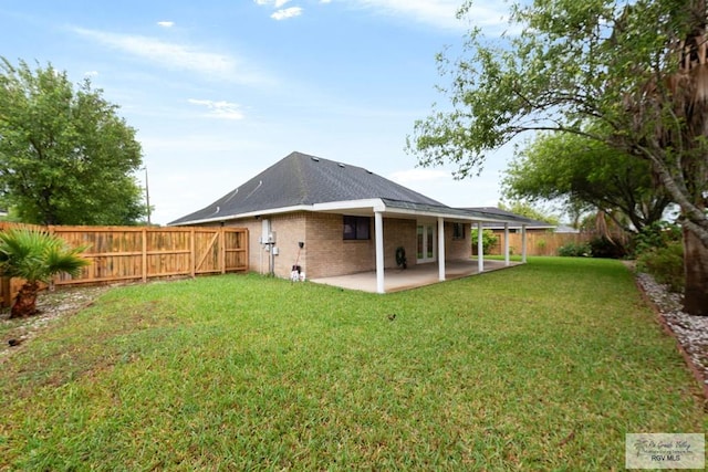 back of house with a patio, brick siding, a yard, a fenced backyard, and roof with shingles