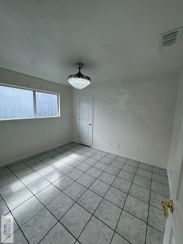 empty room with baseboards, visible vents, and light tile patterned floors