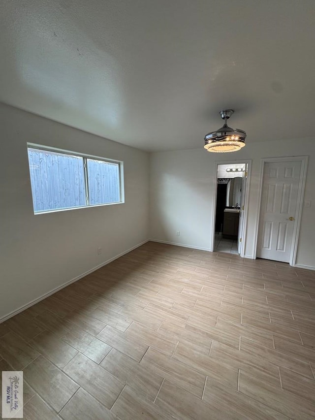 unfurnished bedroom featuring connected bathroom, baseboards, and wood tiled floor