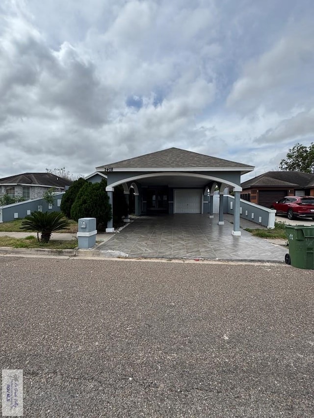 view of front facade featuring driveway, a garage, and roof with shingles