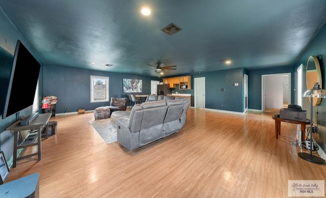 living room with light wood-type flooring and ceiling fan