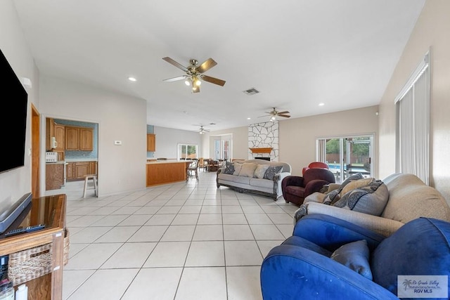 living room with a fireplace, light tile patterned floors, and ceiling fan