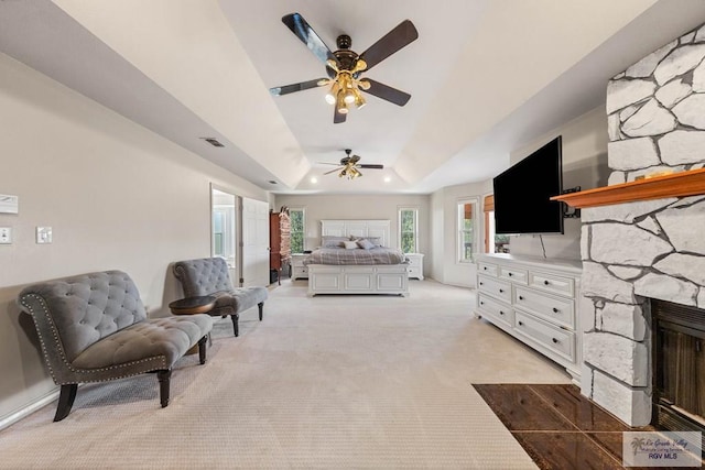 bedroom featuring a fireplace, light colored carpet, and a raised ceiling